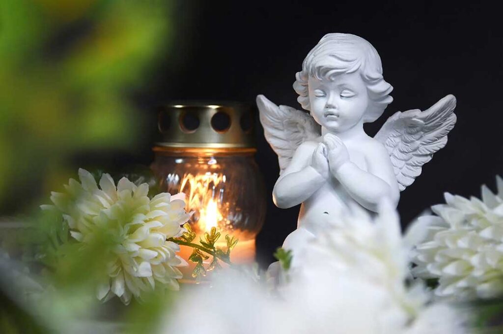 Mourners gathered respectfully around candles, flowers, photographs, and a memorial table during a funeral ceremony