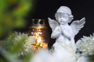 Mourners gathered respectfully around candles, flowers, photographs, and a memorial table during a funeral ceremony